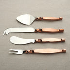 Set of four metal cheese tools with rose gold handles on a gray background