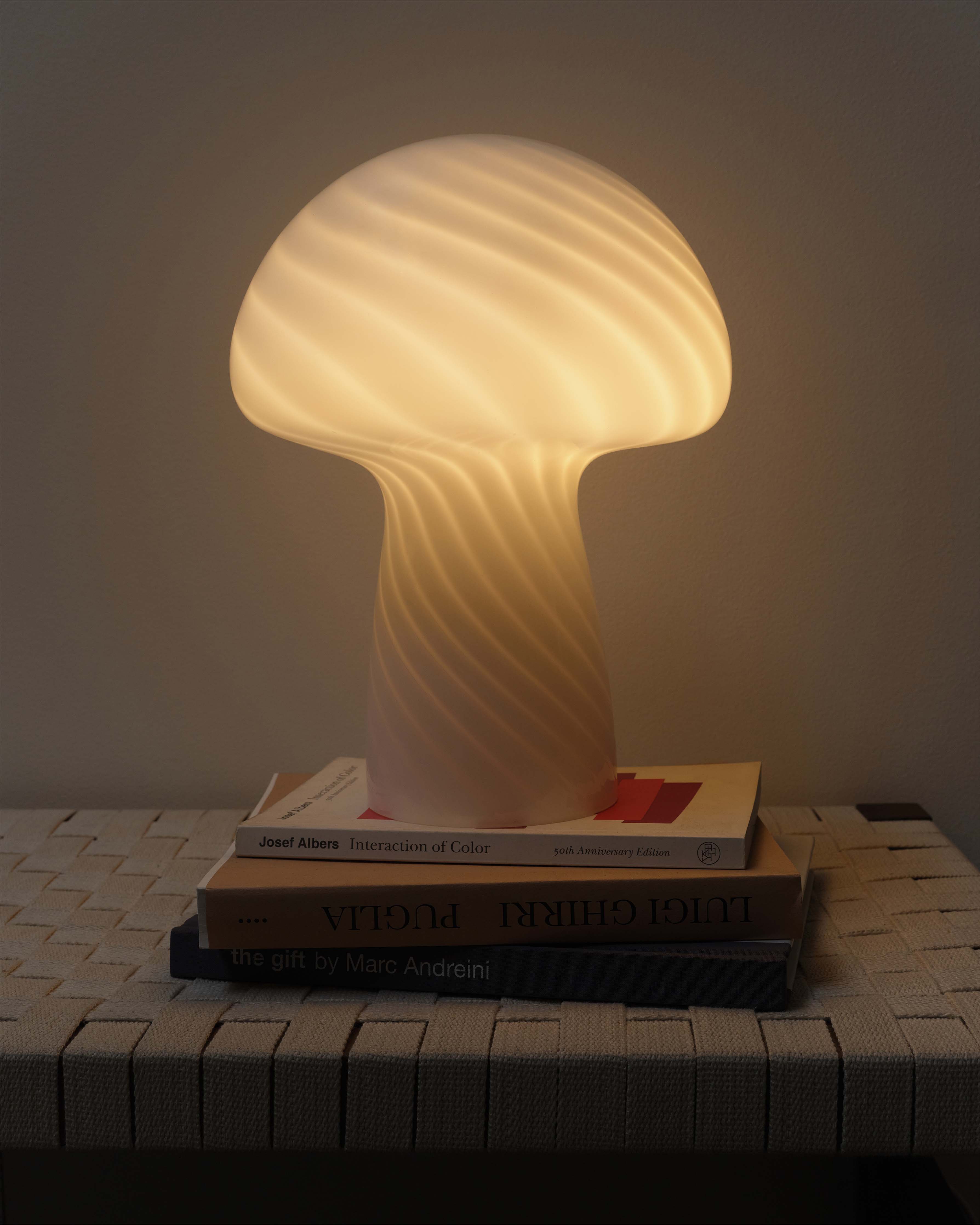 Mushroom-shaped lamp on a stack of books with a warm glow
