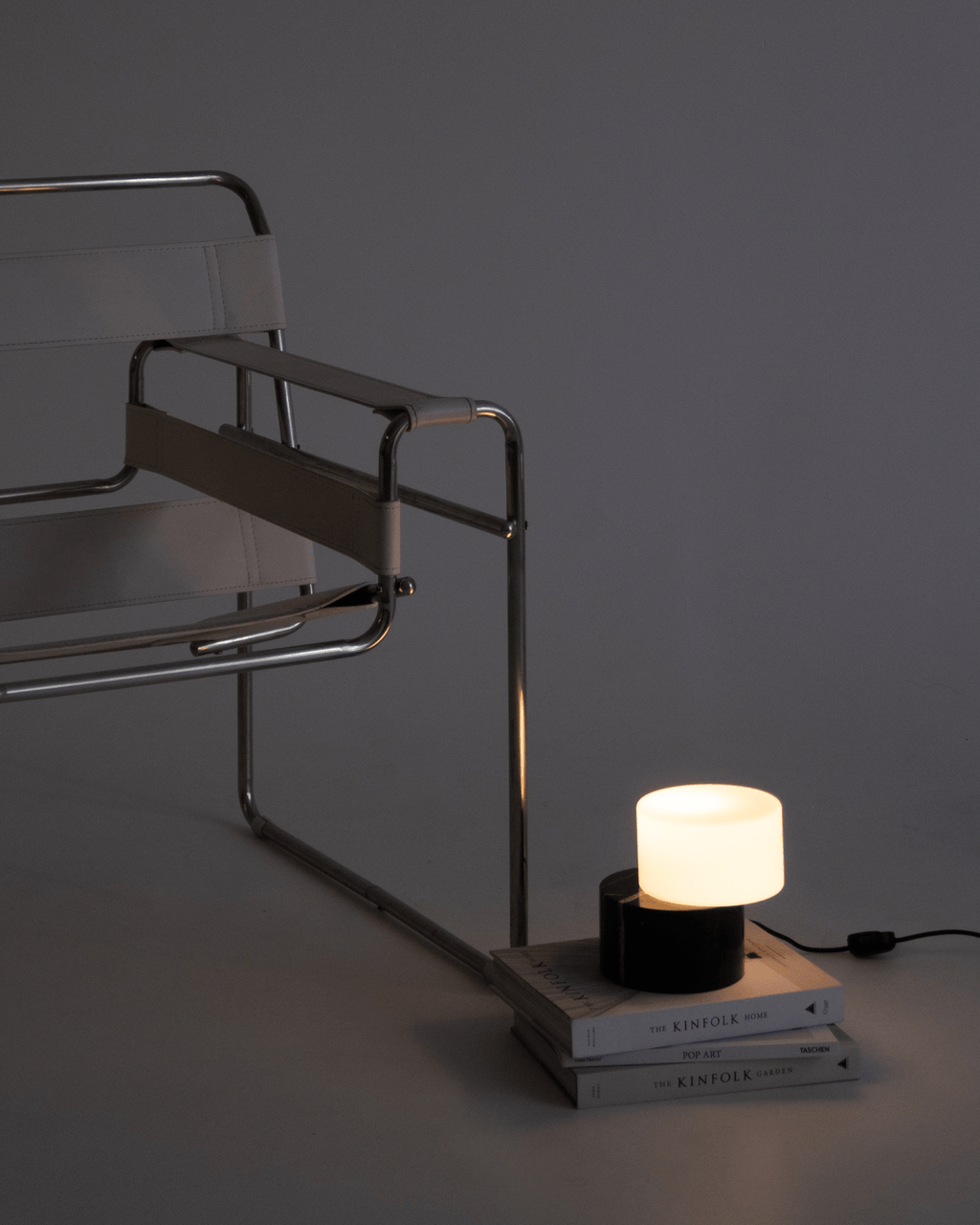 Modern chair with a small lamp on books against a dark background