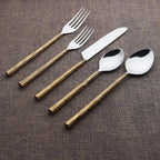 Set of silver cutlery with golden grooved handles on a brown fabric background