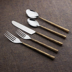 Set of silver cutlery with bronze handles on a brown fabric background