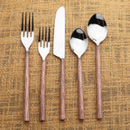 Set of silver cutlery with copper grooved handles on a white background