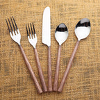 Set of silver cutlery with copper grooved handles on a textured brown background