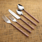 Set of silver cutlery with copper grooved handles on a textured brown background