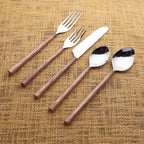 Set of silver cutlery with copper grooved handles on a textured brown surface