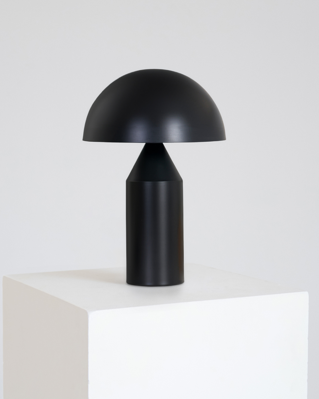 Black table lamp on a white surface with a light gray background