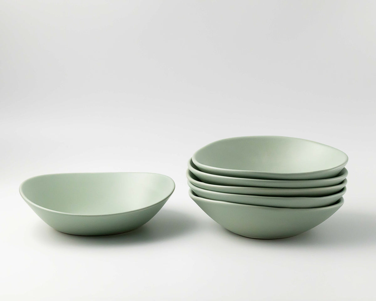 Set of light green ceramic bowls on a white background