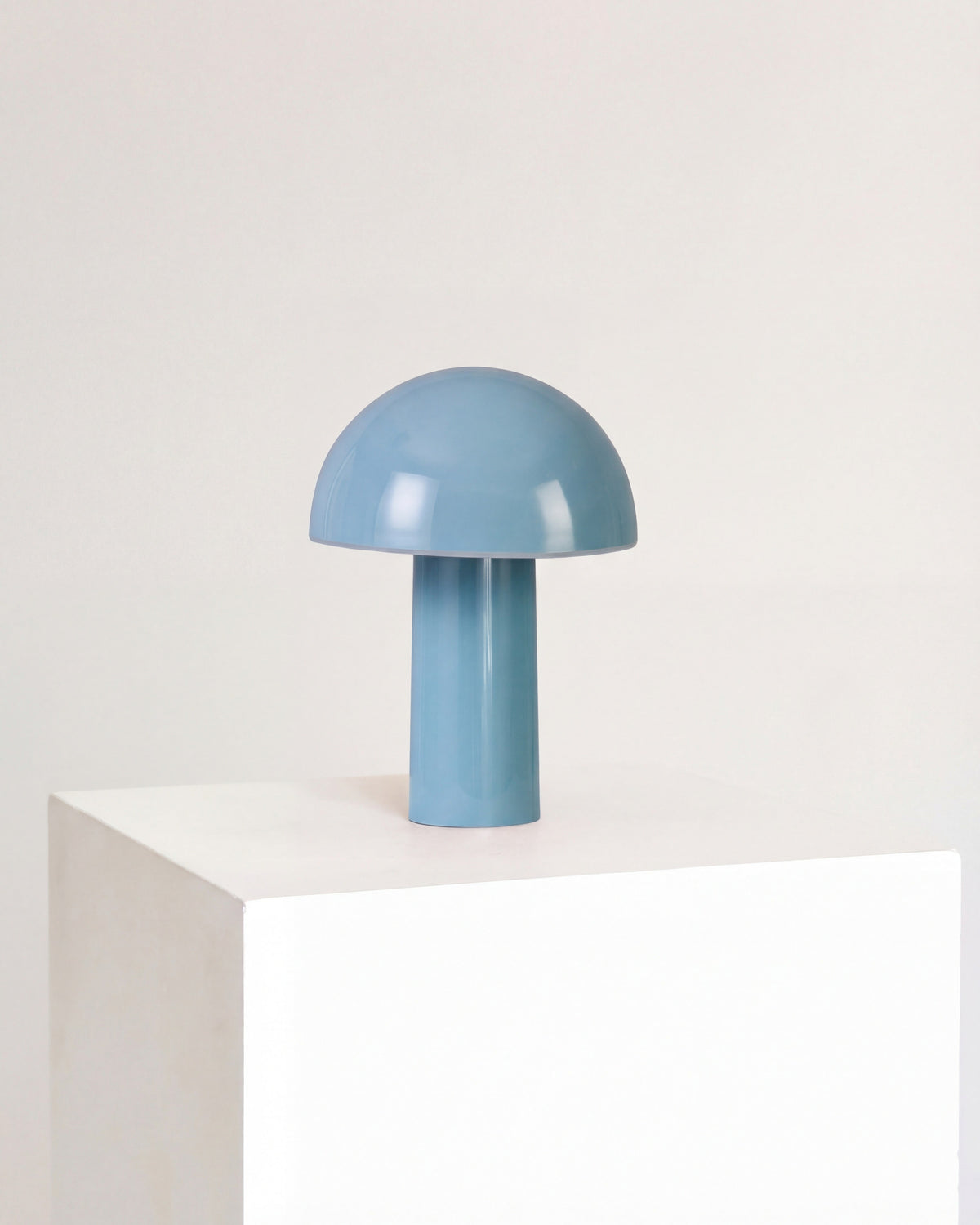 Blue mushroom-shaped lamp on a white pedestal against a white background