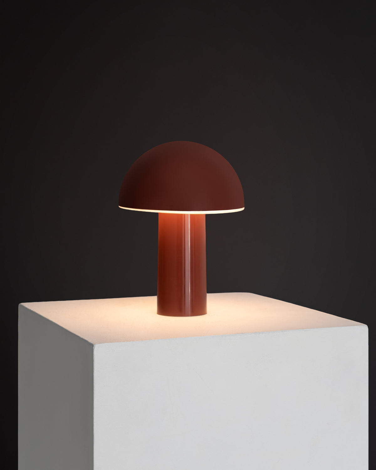 Red Mushroom-shaped table lamp on a white pedestal against a dark background