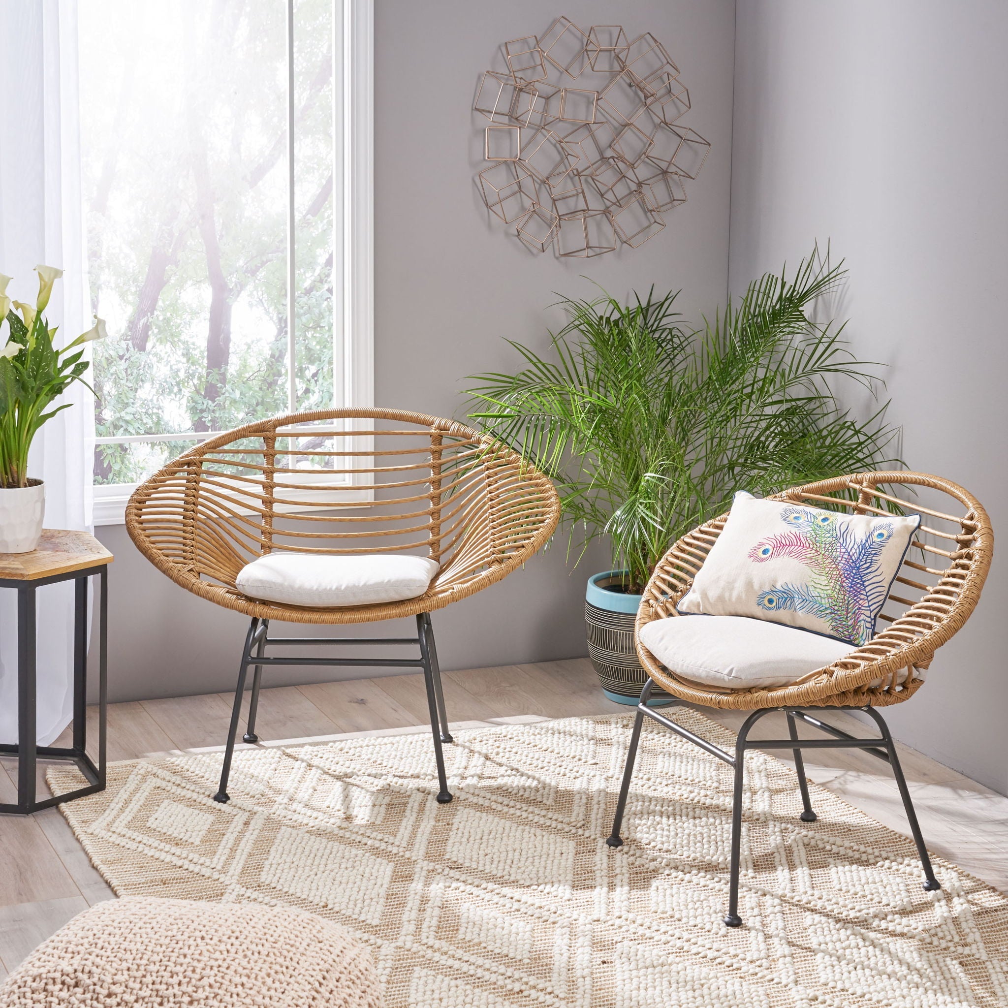 Two wicker chairs with cushions in a room with plants and a rug.