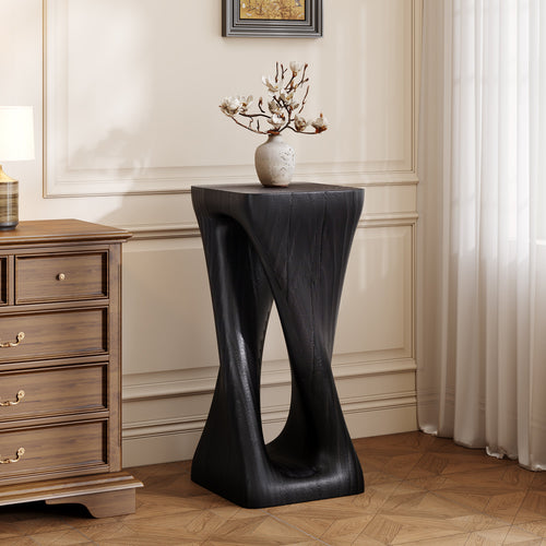 Modern black side table with a vase of flowers in a room with wooden flooring and a dresser.