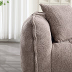 Close-up of a textured brown sofa with a pillow in a room with light-colored curtains.
