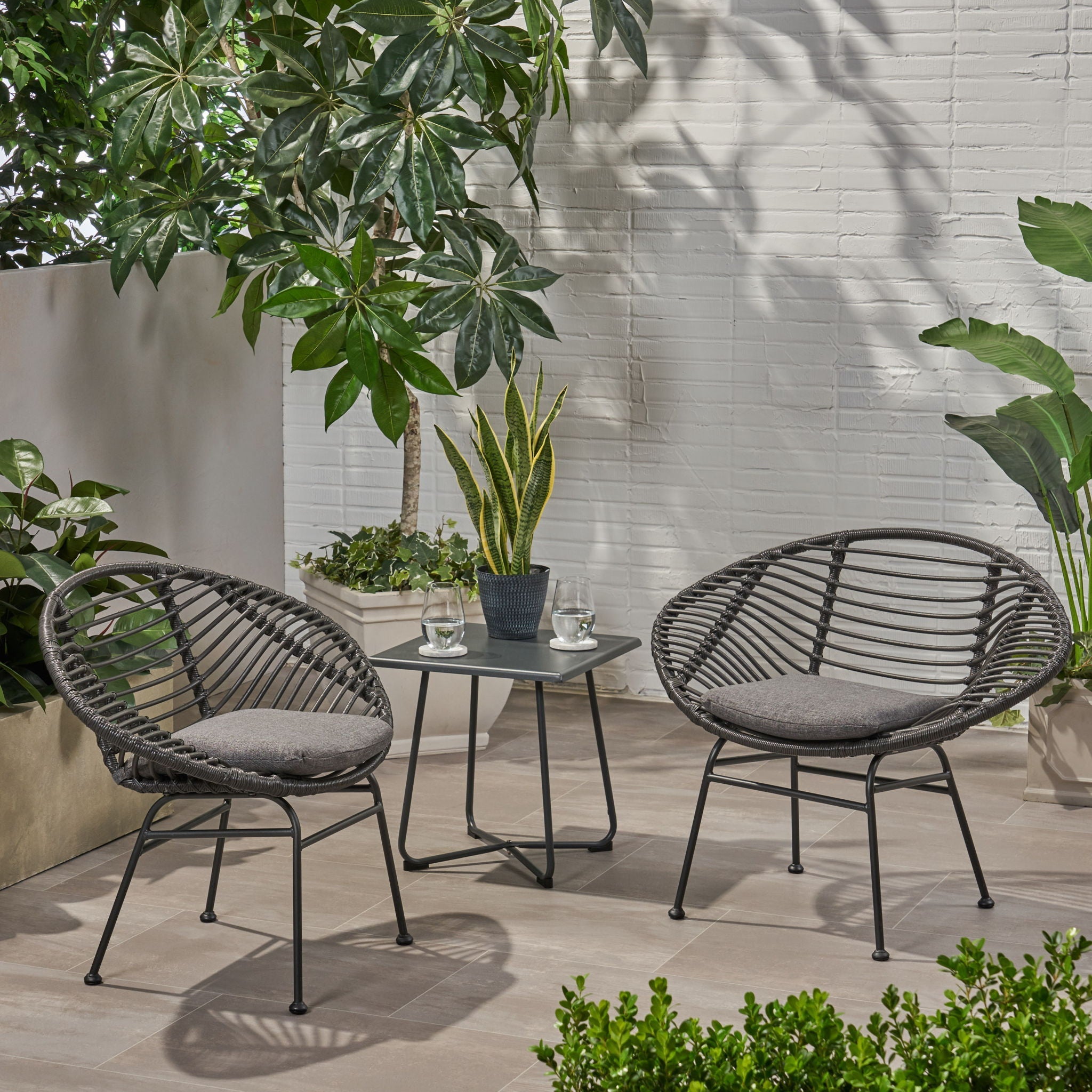 Outdoor patio set with two chairs and a table surrounded by plants on a patio.
