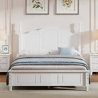 White wooden bed in a bedroom with framed artwork on the wall.