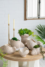 Decorative ceramic vases and planters on a wooden table with a white brick wall background.