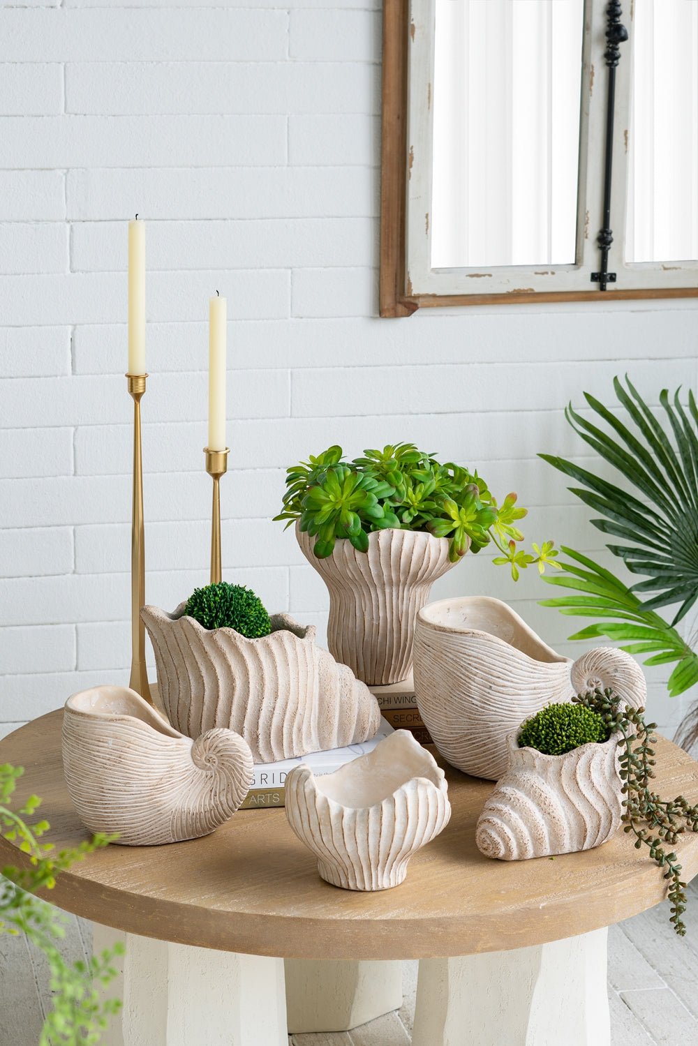 Decorative ceramic vases and planters on a wooden table with a white brick wall background.