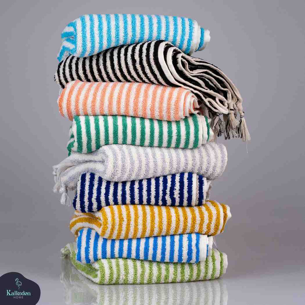 Stack of colorful striped hand towels in multiple colors on a reflective surface