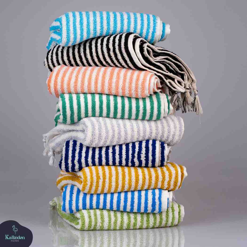Stack of colorful striped hand towels in multiple colors on a reflective surface