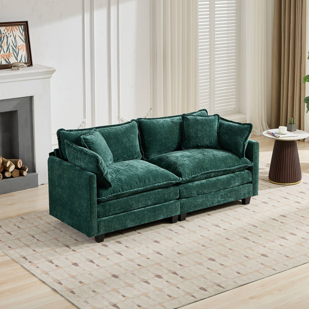 Green sofa in a living room setting with a fireplace and table.