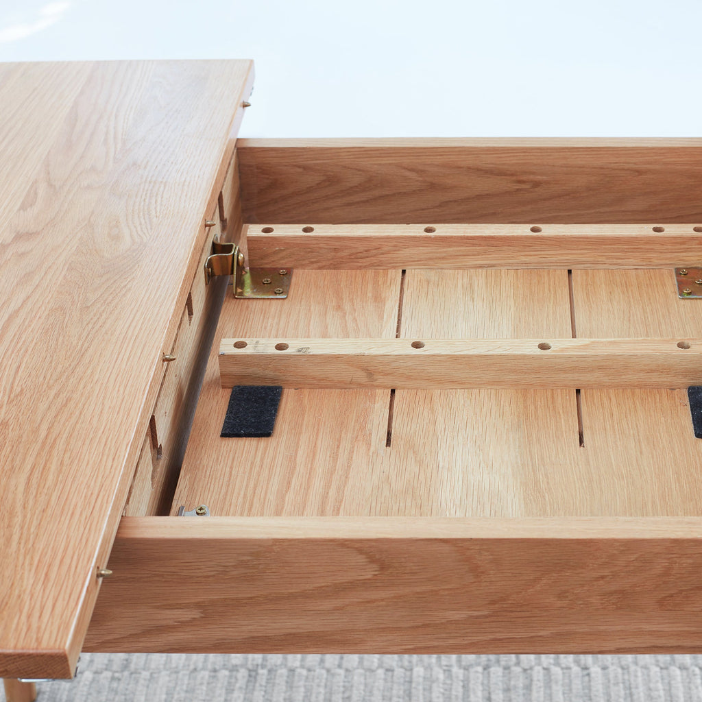 Wooden table with an open extension on a light gray surface