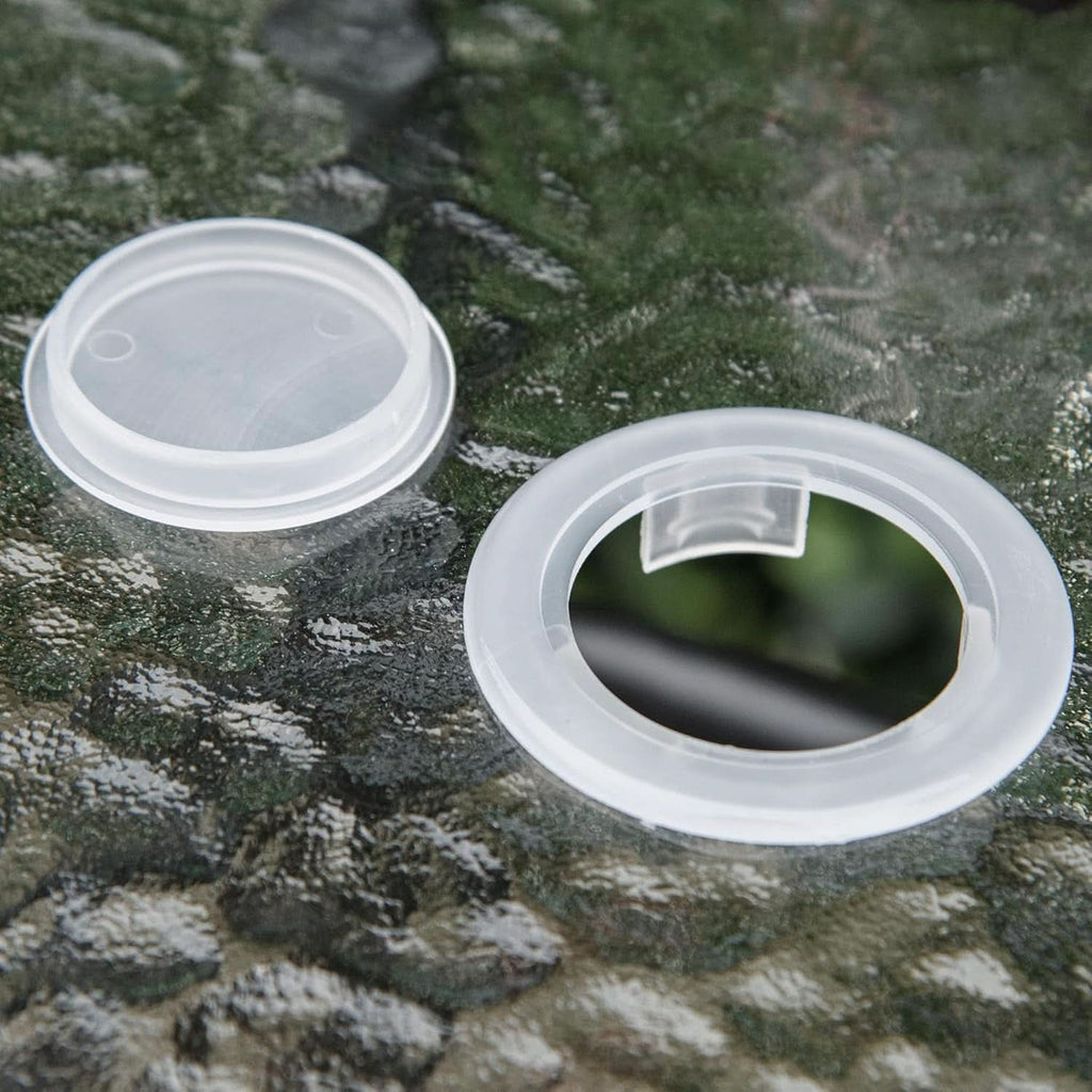 Two clear plastic lids on a textured green surface
