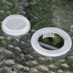 Two clear plastic lids on a textured green surface