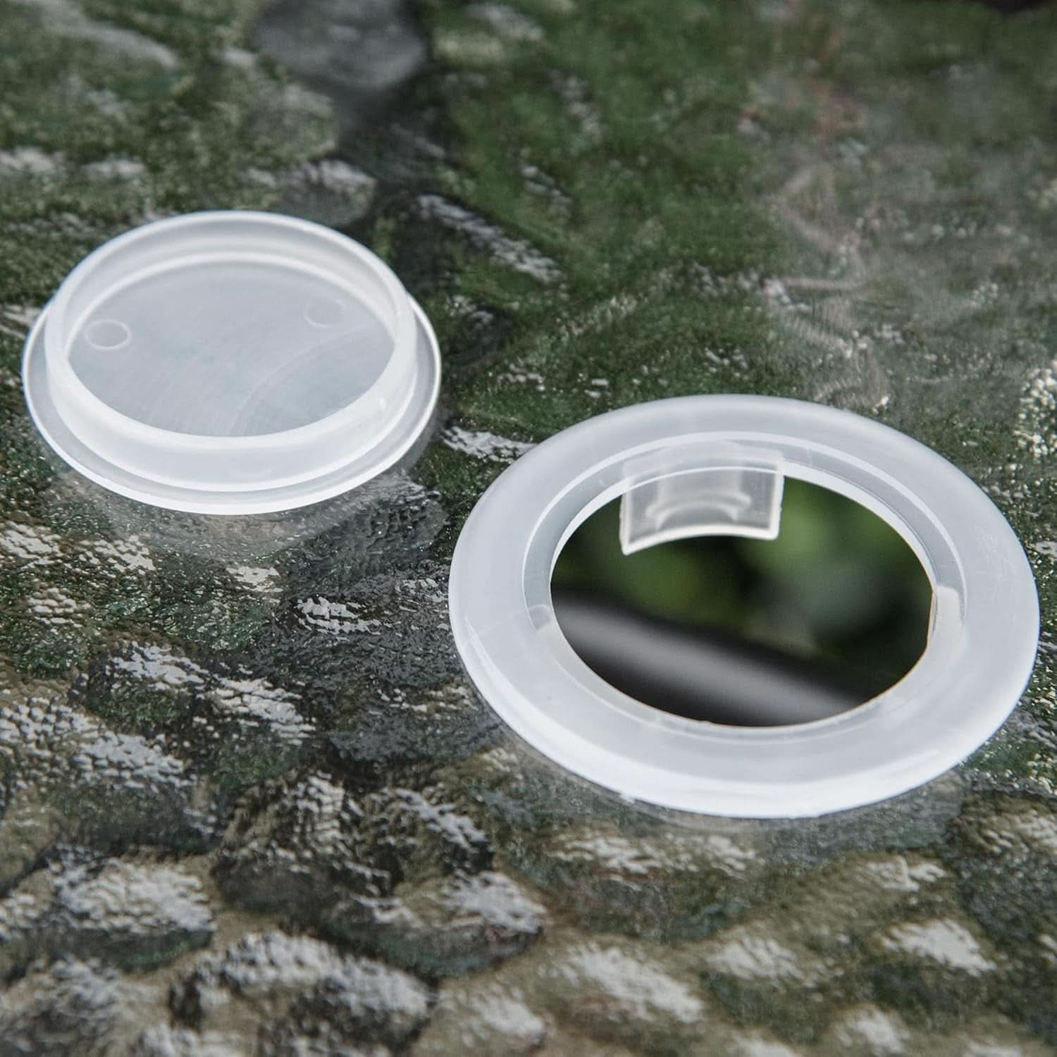Two clear plastic lids on a textured green surface
