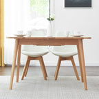 Wooden dining table with four white chairs in a bright room.