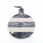 Round marble serving board with gray and white horizontal stripes, featuring a handle with a dark brown hanging cord and four white circular accents, shown on a plain white background.