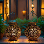 Two illuminated decorative lanterns on a surface with a blurred background of plants and lights.