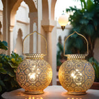 Two ornate gold lanterns on a table with a blurred architectural background