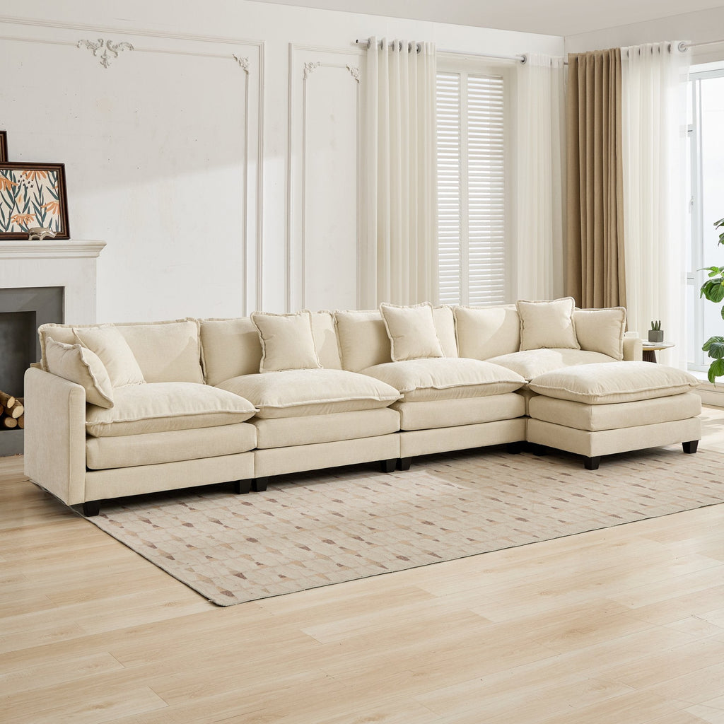 Beige sectional sofa in a living room with light wood flooring and large windows.