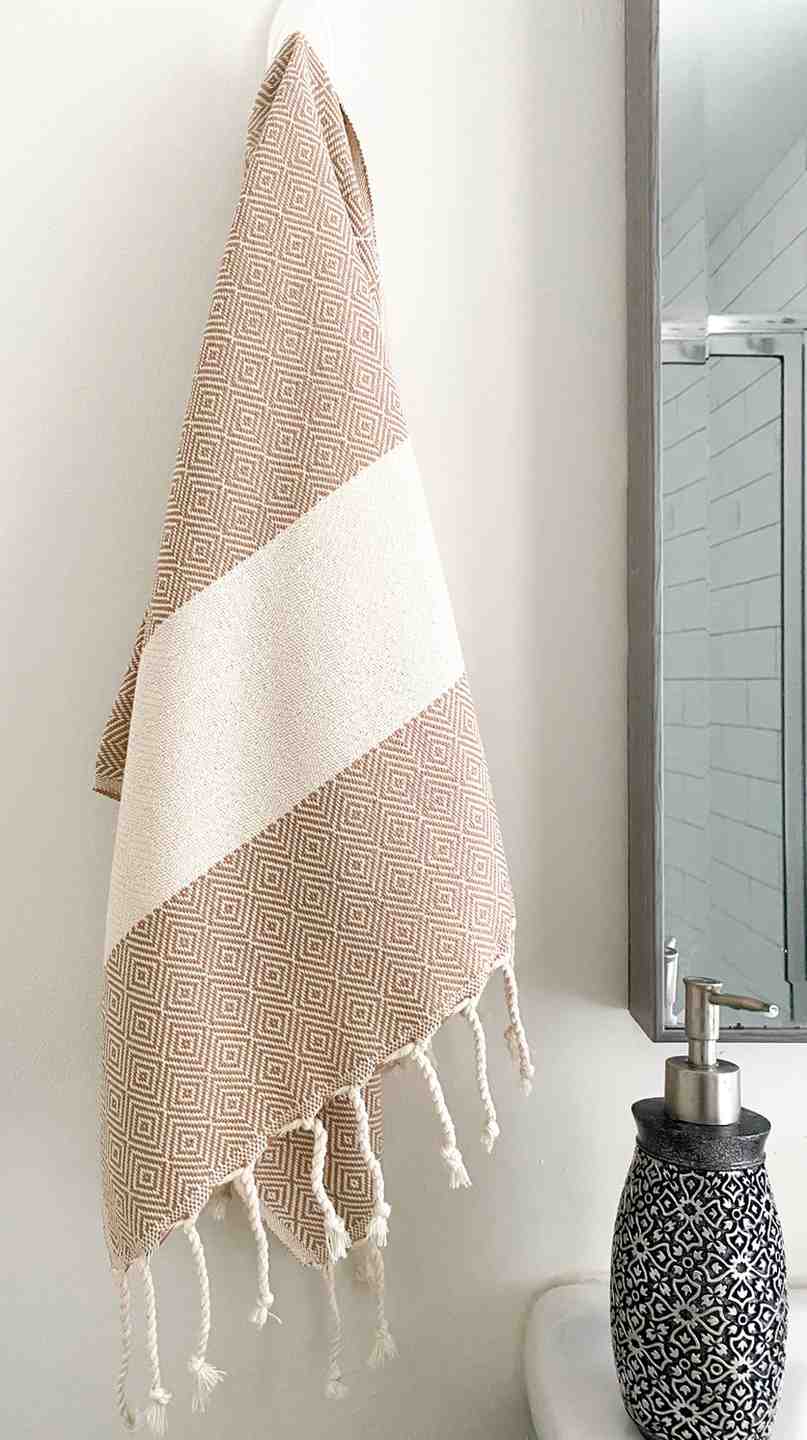 Beige diamond pattern hand towel with tassels hanging in modern bathroom