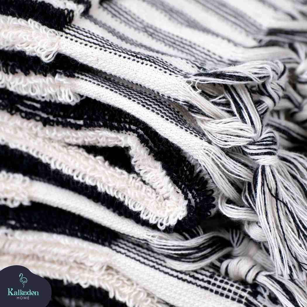 Close-up of stacked black and white striped hand towels with fringe detail