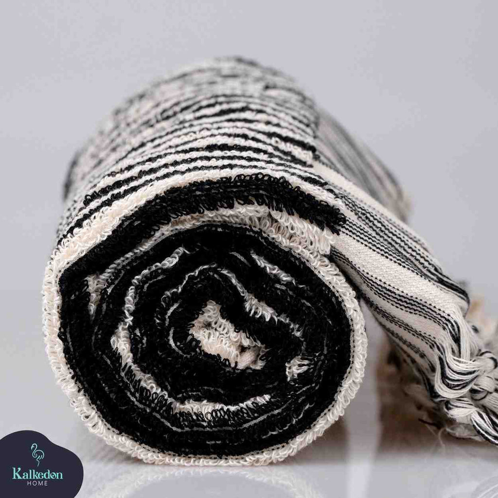 Folded black and white striped hand towel with textured pattern on plain background