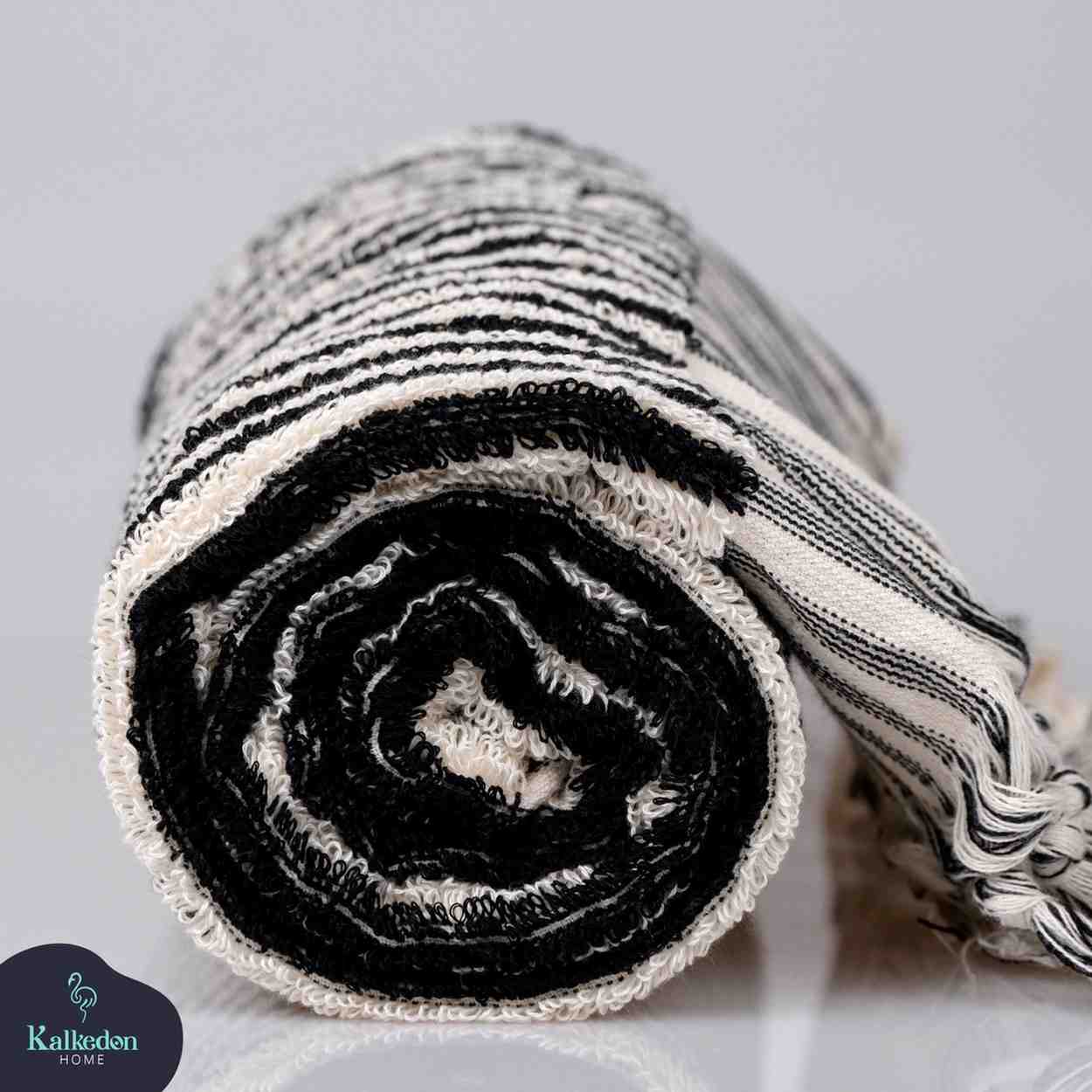 Folded black and white striped hand towel with textured pattern on plain background