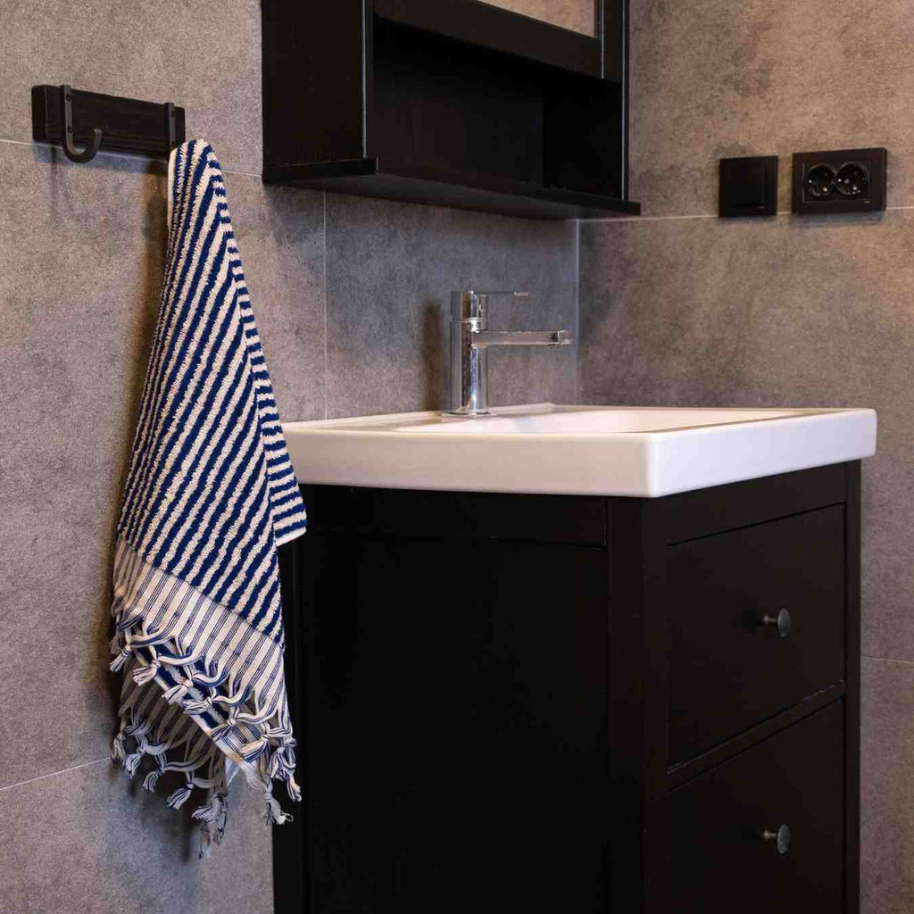 Black and white striped hand towel hanging near modern bathroom sink