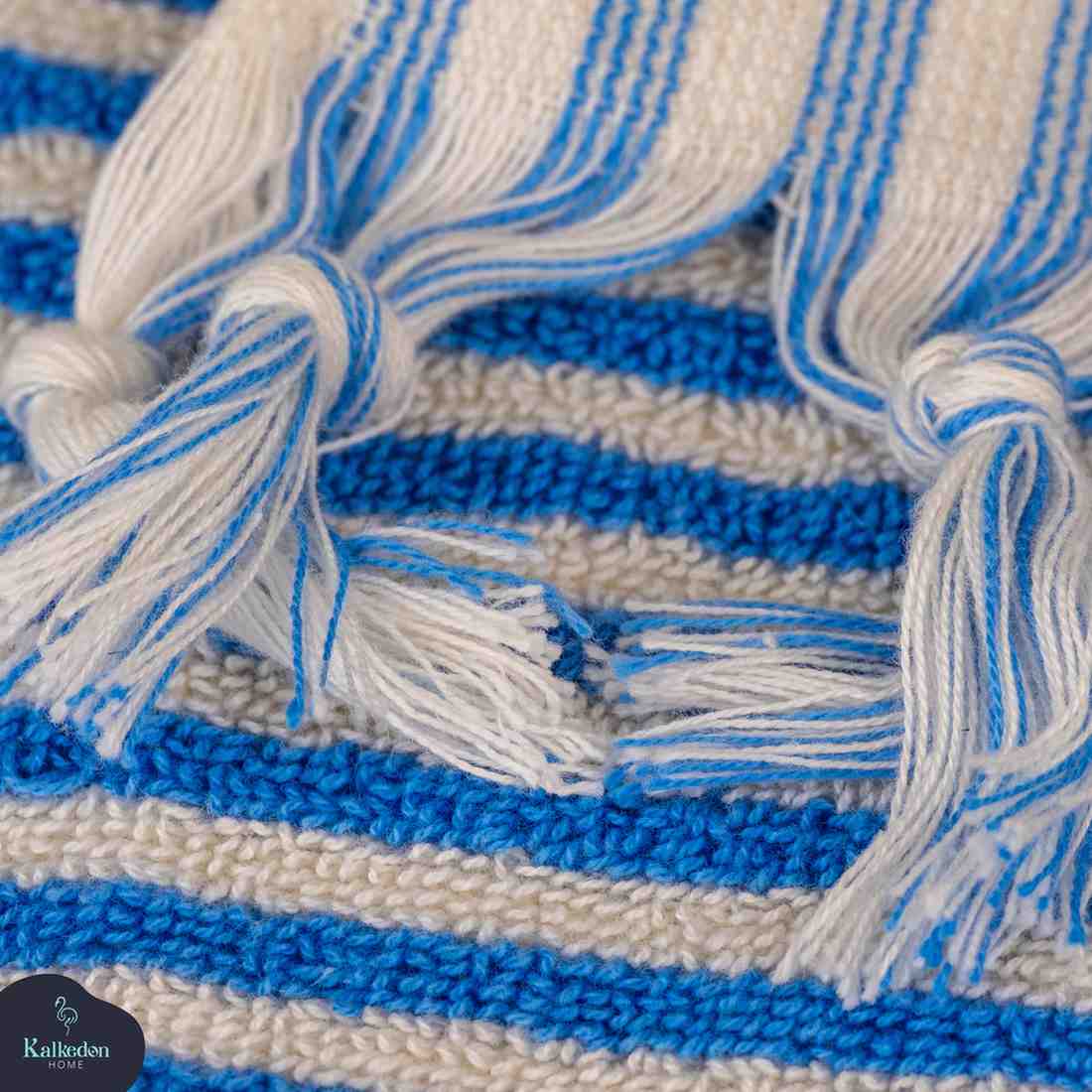 Close-up of blue and white striped hand towel with woven texture and tasseled edges