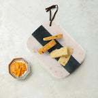 Marble and slate board with crackers and a small container of spread on a light background