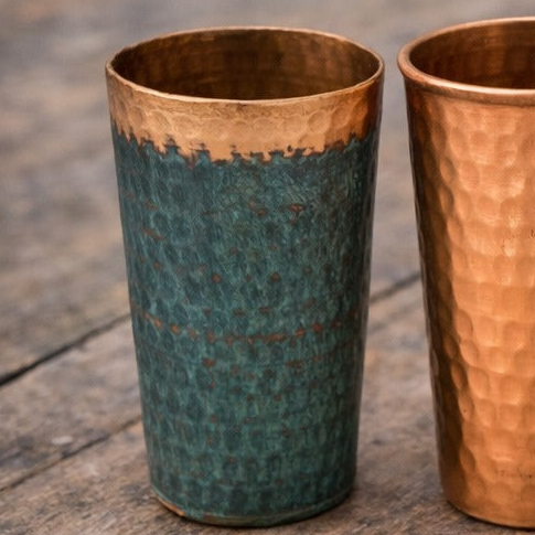 Tumbler with blue body and copper top on a wooden surface background