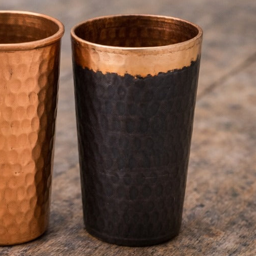 Tumbler with black body and copper top on a wooden surface background