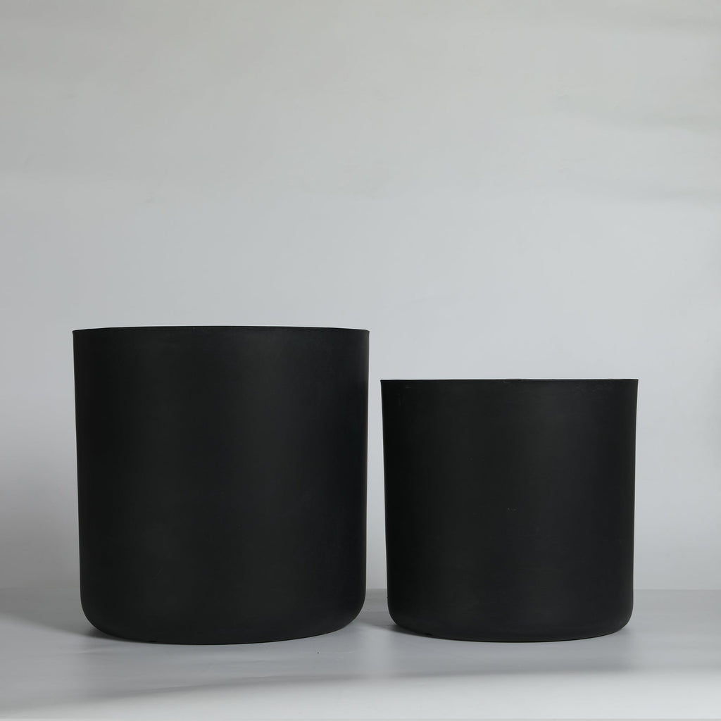 Two black cylindrical pots on a light gray background