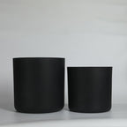 Two black cylindrical pots on a light gray background