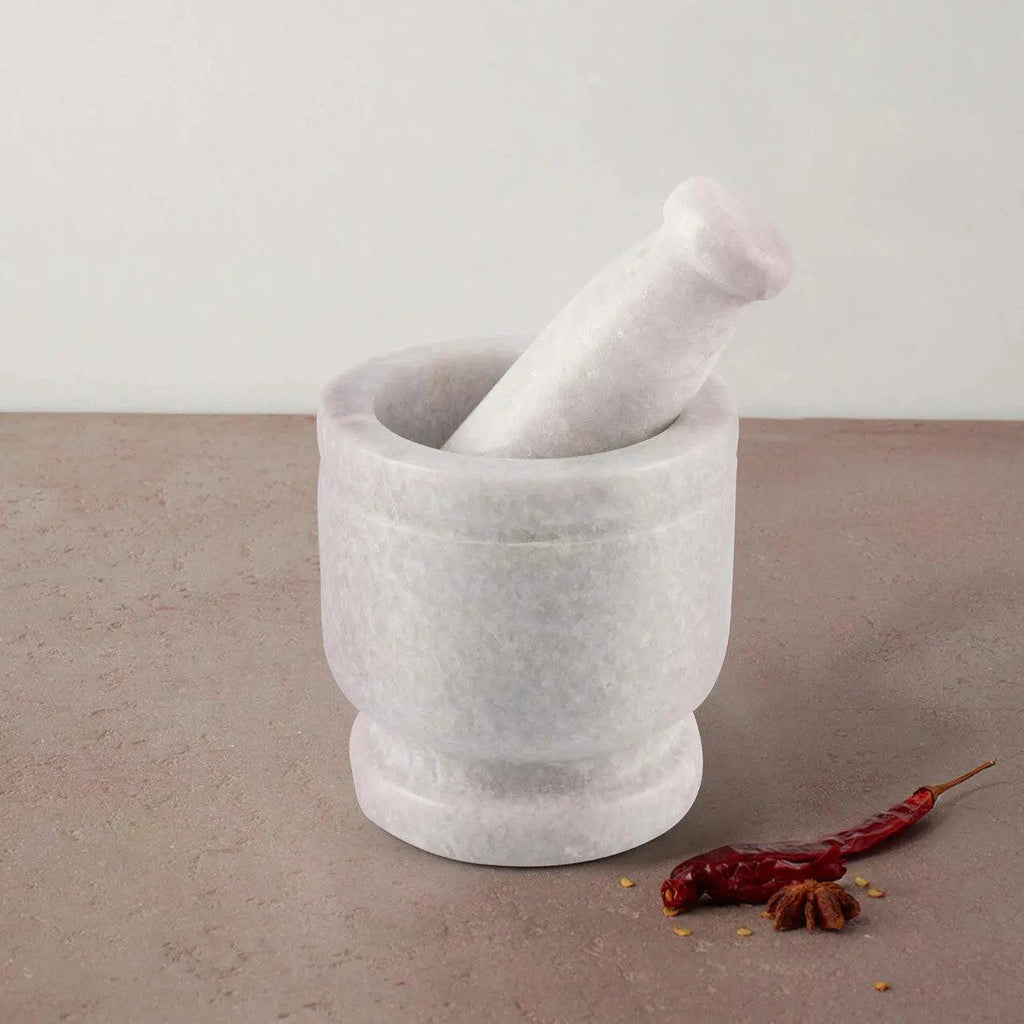 Marble mortar and pestle with a red chili pepper on a gray surface
