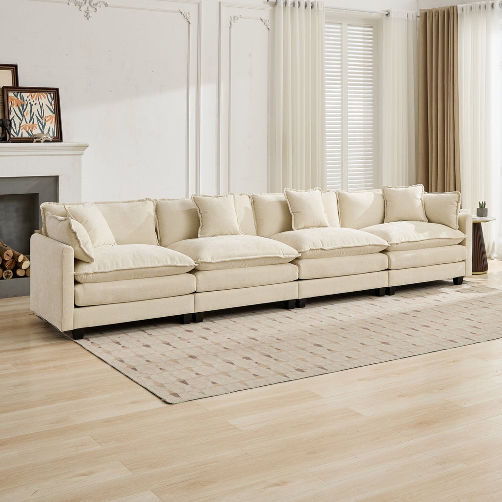 Beige sectional sofa in a living room with wooden floor and large windows.
