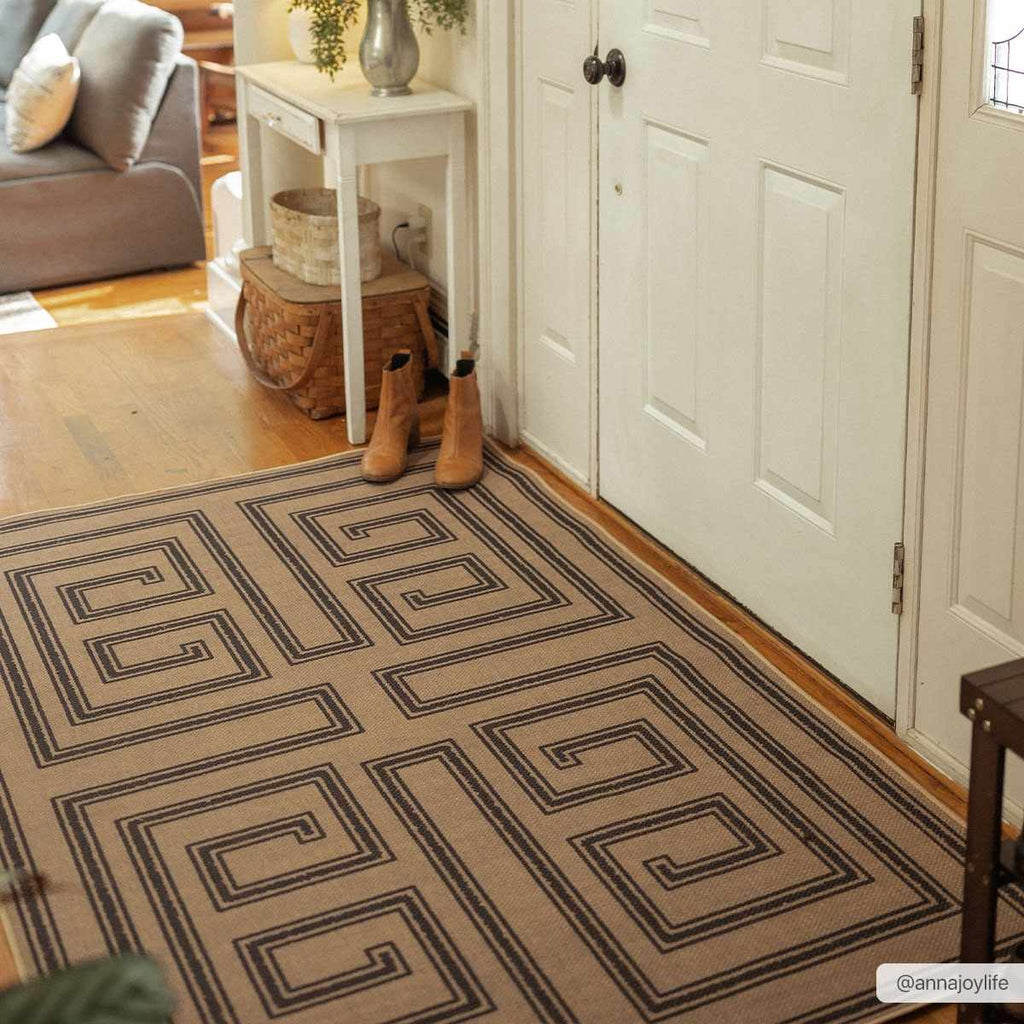 Patterned rug on a wooden floor with a white door and small table in the background.