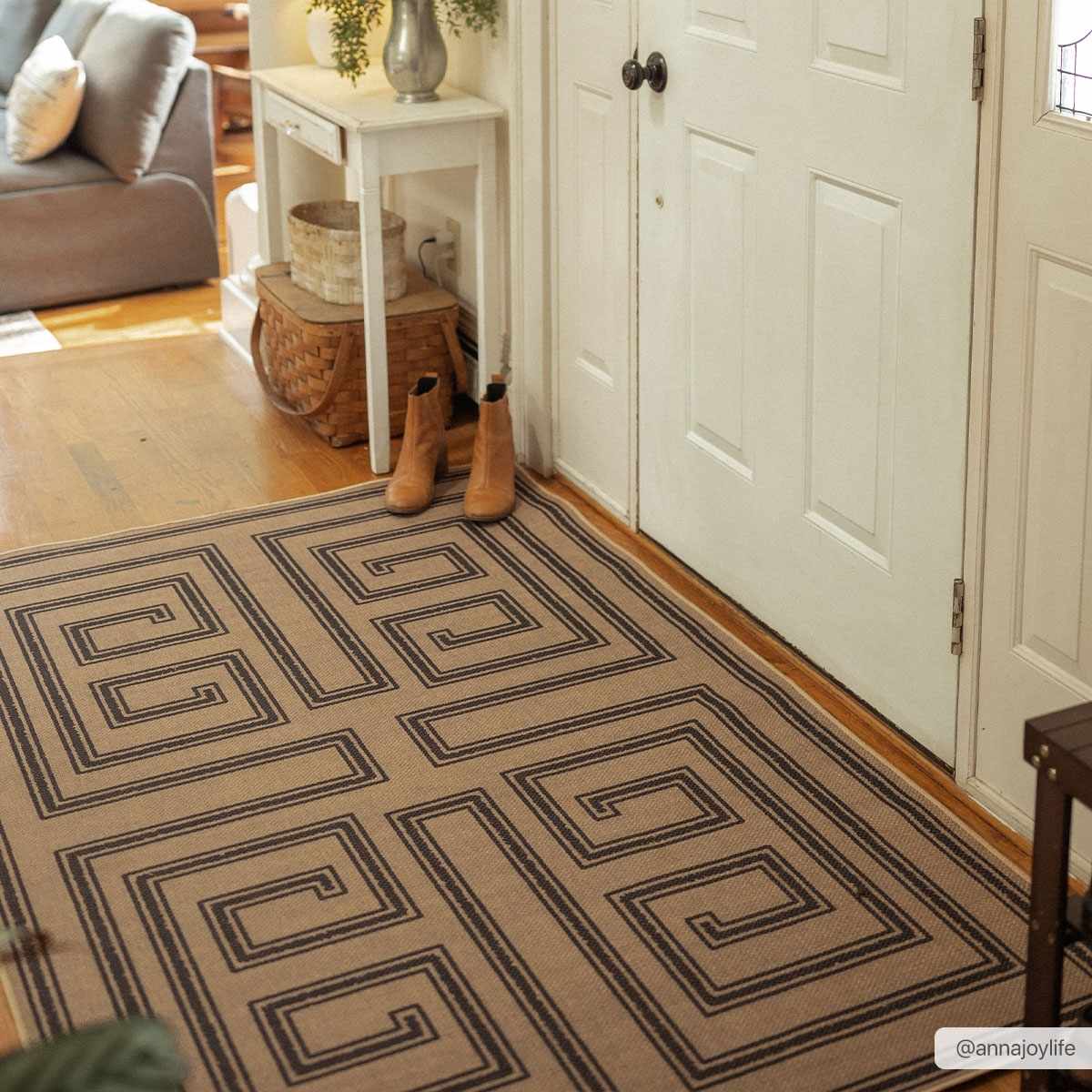 Patterned rug on a wooden floor with a white door and small table in the background.