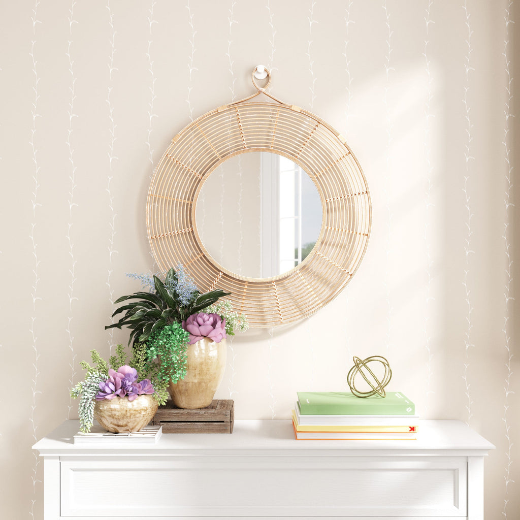 Round wicker mirror on a wall above a white console table with decorative items.