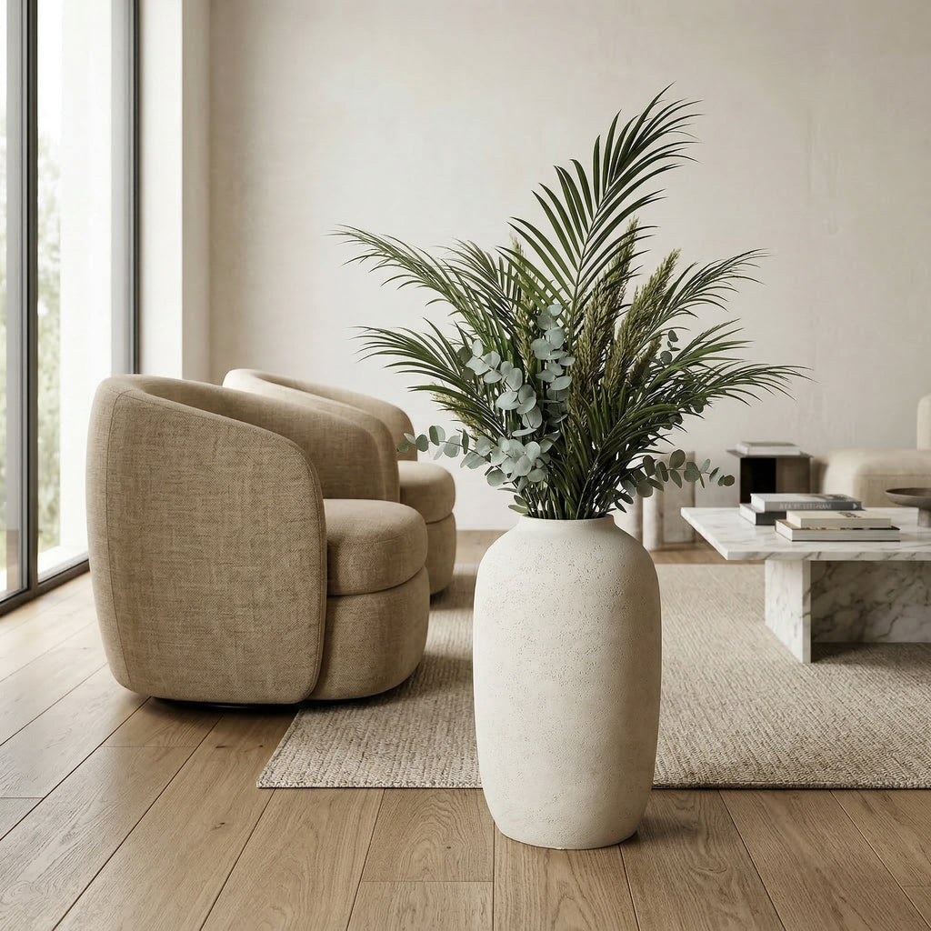 Modern living room with beige armchair, large vase with plants, and coffee table.