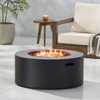 Black fire pit table with flames in a modern outdoor setting with a chair and table.